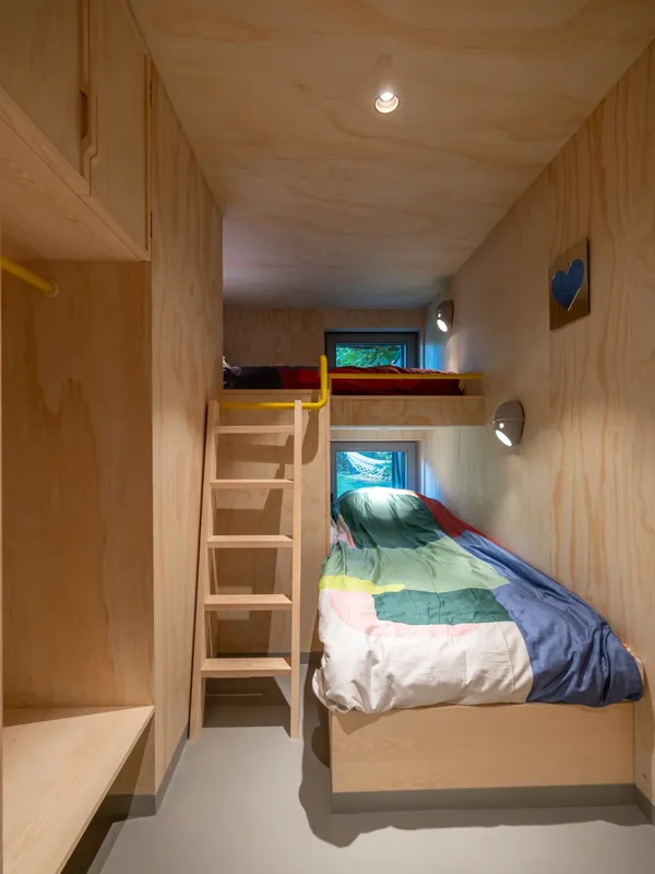 Bedroom with a high and a low bed and a small wooden ladder