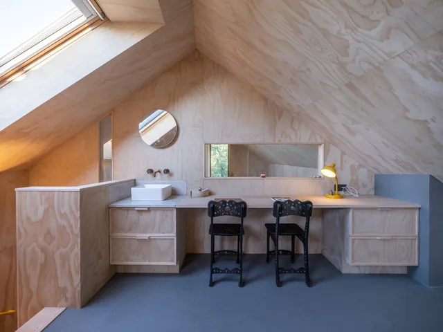 Bureau onder het schuine dak met twee zwarte stoelen