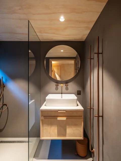 Badkamer met ronde spiegel en houten wastafelmeubel